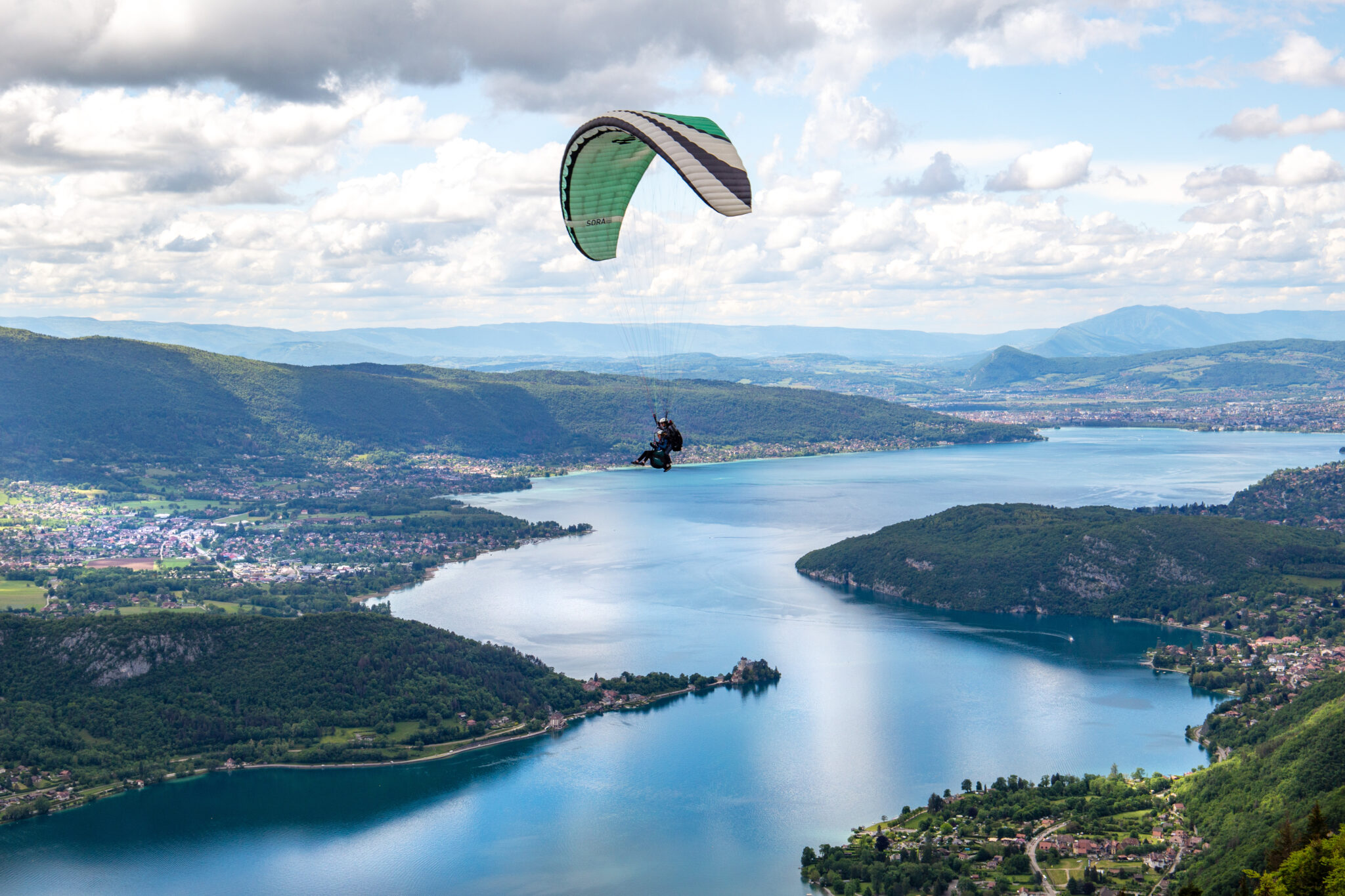 Paragliding over Annecy lake with mountain landscape.